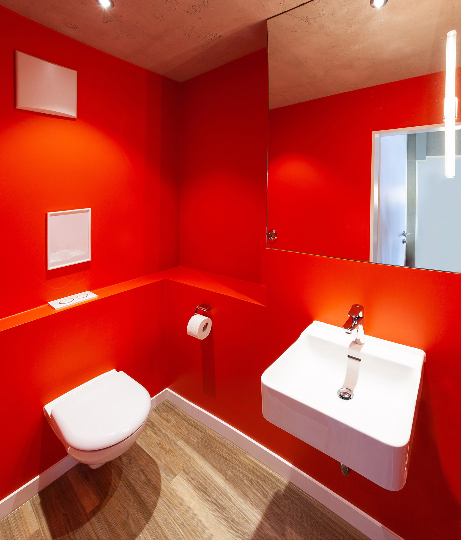 Das Patienten-WC erstrahlt in leuchtend roter Wandfarbe.