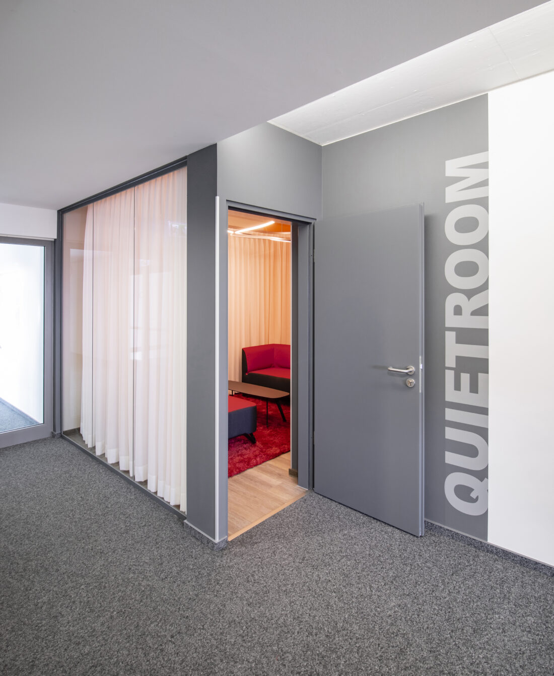 Außenansicht des Quietroom. Einsicht durch die Glaswand kann mit einem Vorhang verhindert werden. Abschließbarer Raum für Privatsphäre.